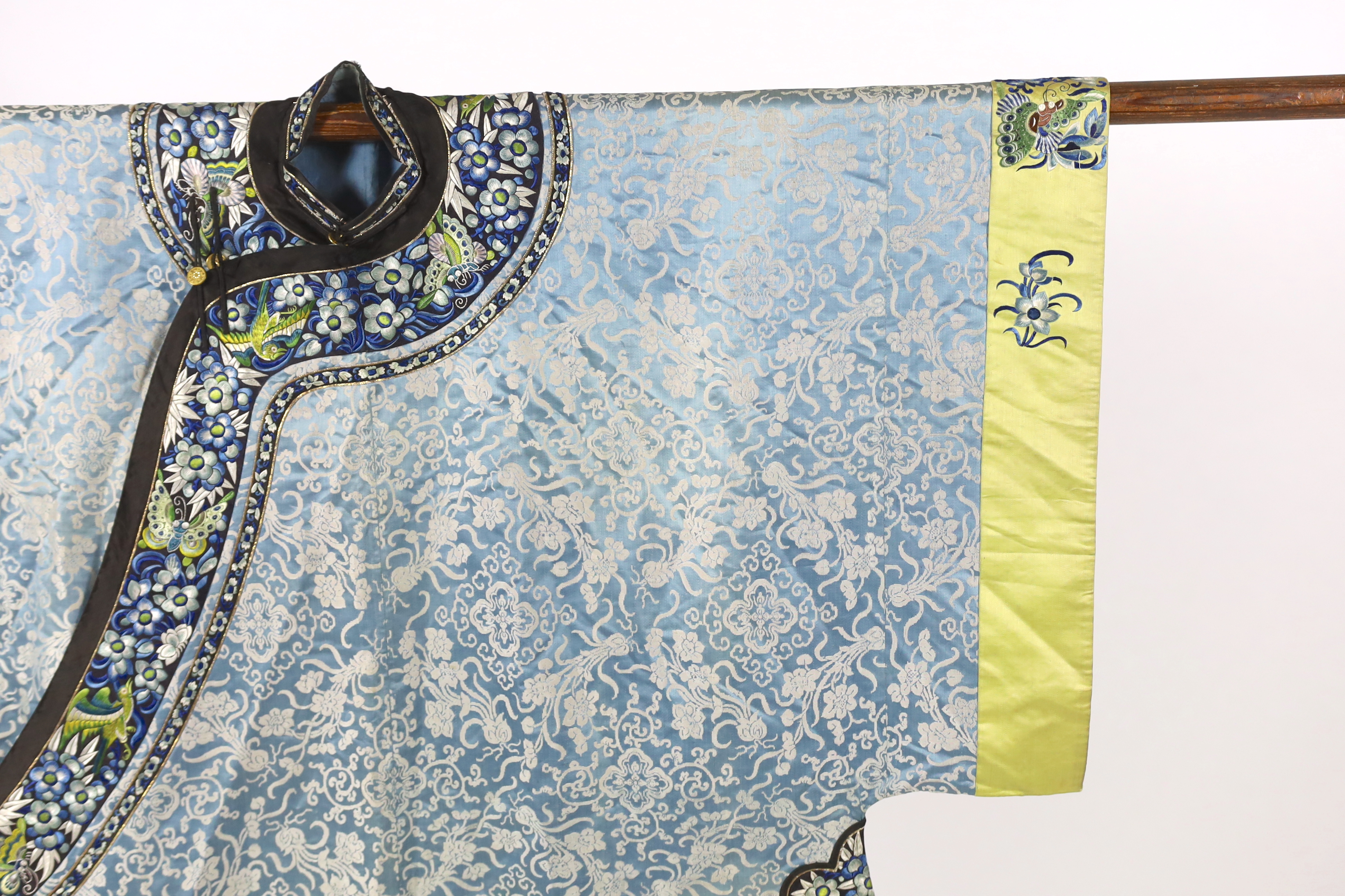 A late 19th / early 20th century silk damask robe, edged with highly ornate embroidered silk braiding, edged with fine gold and black borders, with yellow silk embroidered sleeve bands, the blue silk lining is faded in p
